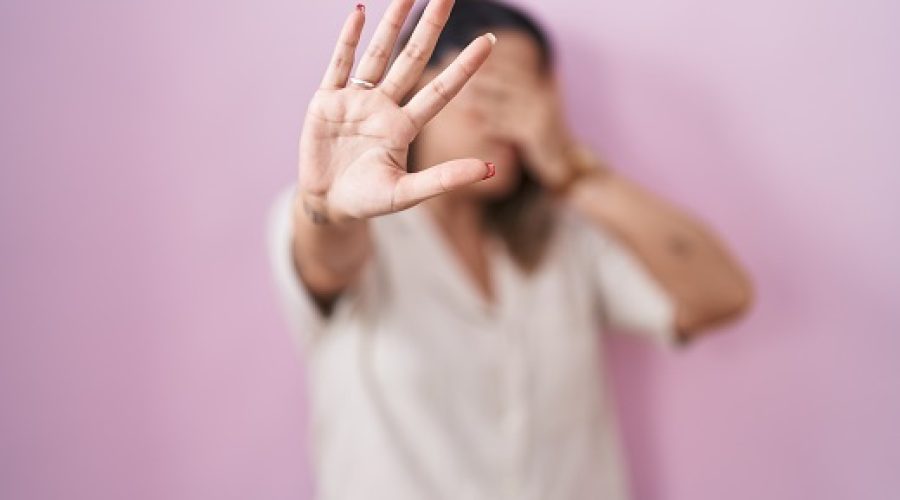 Blonde woman standing over pink background covering eyes with hands and doing stop gesture with sad and fear expression. embarrassed and negative concept.